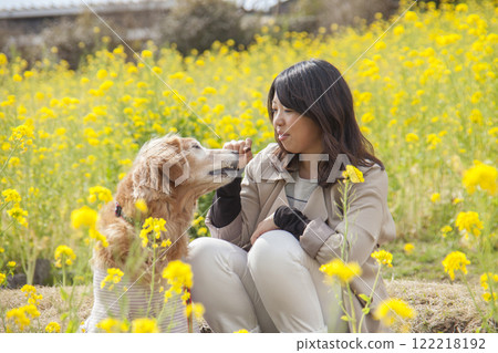 Owner and golden retriever snuggling together in a rapeseed field Owner and golden retriever snuggling together in a rapeseed field 122218192