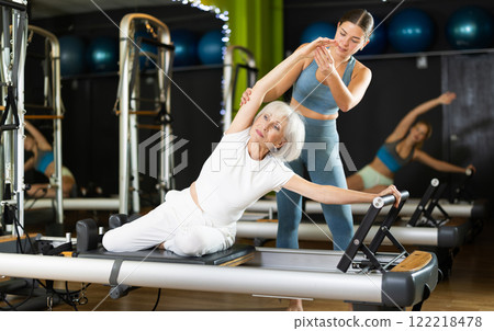 Woman with trainer exercising on Pilates platform 122218478