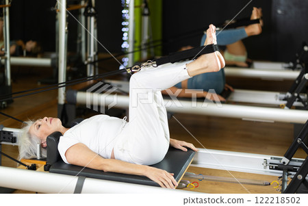 Mature slim woman lies on the reformer platform 122218502