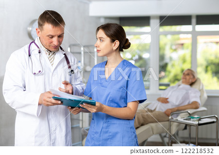 Two doctors are carefully examining patient medical history Two doctors are carefully examining patient medical history 122218532