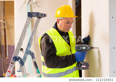 European repair man with screw gun working in apartment 122218561