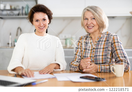 Smiling old and middle-aged women posing at the kitchen-table 122218571