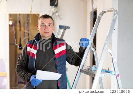 Professional electrician reads electrical wiring plan Professional electrician reads electrical wiring plan 122218636
