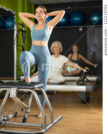 Woman doing exercises on pilates chair in fitness studio 122218701
