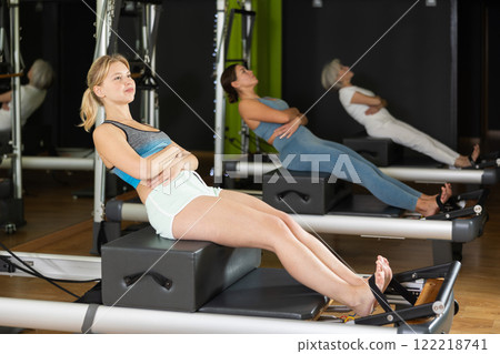 Young woman sitting on box set equipment reformer performs for abdominal muscles 122218741