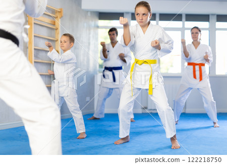 Teen girl with family repeat movements and learn fighting techniques during martial arts lesson Teen girl with family repeat movements and learn fighting techniques during martial arts lesson 122218750