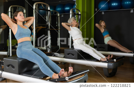 Woman in sportswear sitting on reformer platform Woman in sportswear sitting on reformer platform 122218821