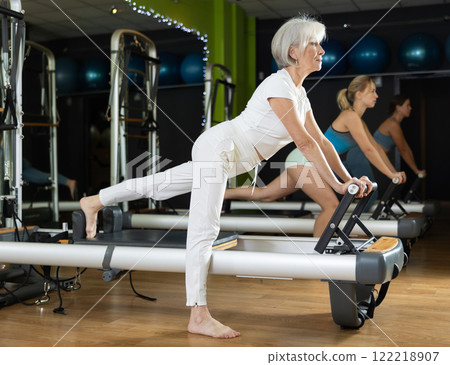 Mature woman performs exercises for the glutes and legs Mature woman performs exercises for the glutes and legs 122218907