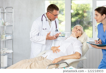 Male beautician giving consultation to woman patient with mirror in aesthetic clinic 122218933