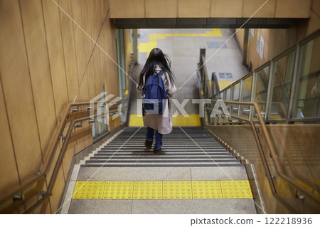 A young elementary school girl descending the stairs at a train station platform in winter 122218936