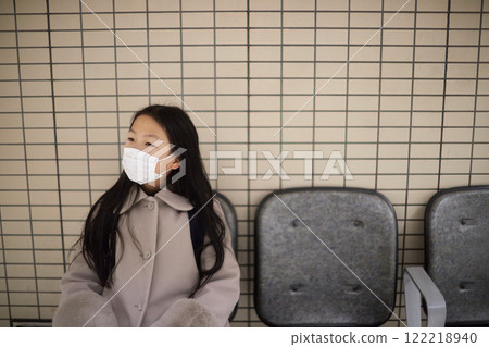 A young elementary school girl waiting for a train on a winter train platform 122218940