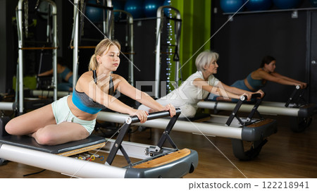 Woman holding the reformer and doing the exercise 122218941