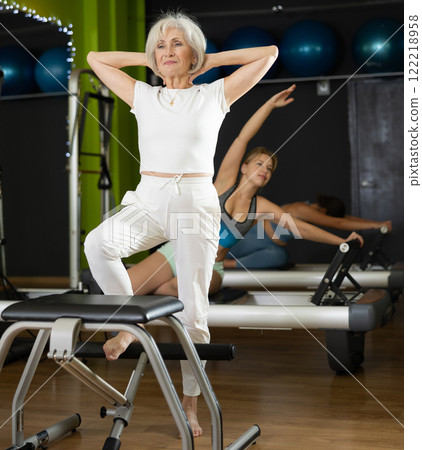 Senior woman perform pilates exercises using lifes beach pilates chair 122218958