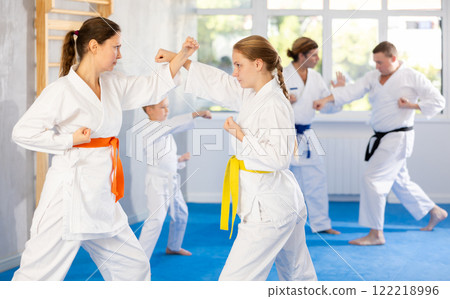 Teen girl is paired with mother to learn how to strike and rehearses blocking opponent 122218996