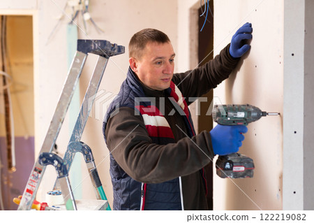 Repair man with drill working in apartment Repair man with drill working in apartment 122219082