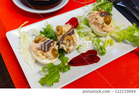 Stuffed eggs with cheese filling and olives, served with lettuce Stuffed eggs with cheese filling and olives, served with lettuce 122219084