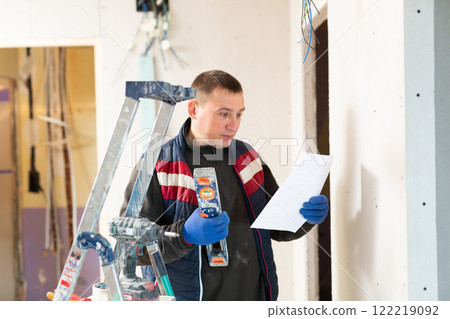 Builder standing at indoors building site, reading document Builder standing at indoors building site, reading document 122219092