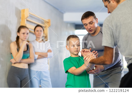 Trainer at self-defense training teaches students technique of grabbing opponent's palm on man 122219124