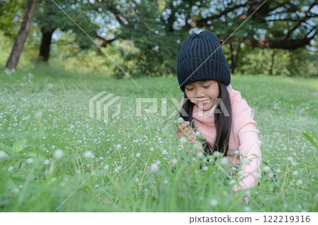 A young girl joyfully exploring wildflowers in a sunny green meadow. A young girl joyfully exploring wildflowers in a sunny green meadow. 122219316