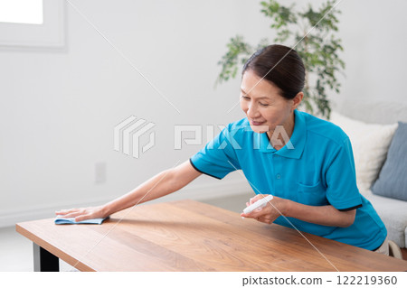 Senior female housekeeper cleaning the table Senior female housekeeper cleaning the table 122219360