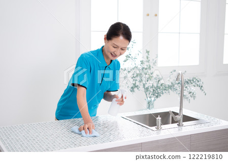 Senior female housekeeper cleaning the kitchen Senior female housekeeper cleaning the kitchen 122219810
