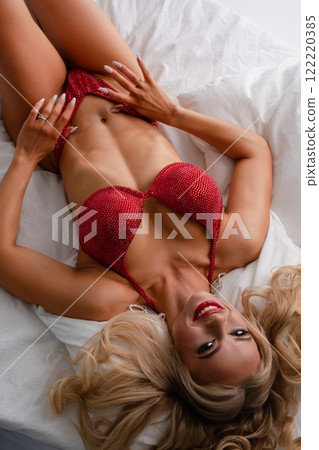 Woman in red lingerie poses on a bed showcasing fitness and style 122220385