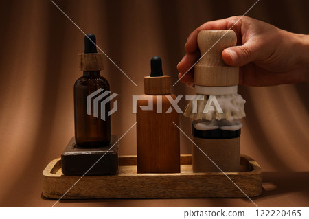 Men's shaving tools, soap, cosmetics bottles and hand on brown background 122220465