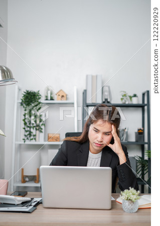 Focused woman in a home office setting, working on a laptop surrounded by plants and modern decor. 122220929