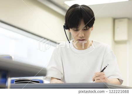 Students taking a test wearing headsets Students taking a test wearing headsets 122221088