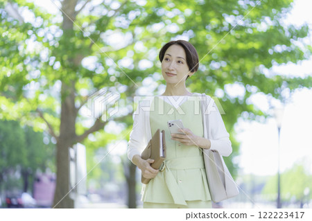 一位女商人拿著筆記本和智慧型手機在新鮮的綠色植物中的肖像 一位女商人拿著筆記本和智慧型手機在新鮮的綠色植物中的肖像 122223417