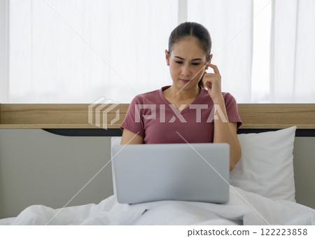 Asian woman in casual clothe using laptop computer to work in bed in the morning. 122223858