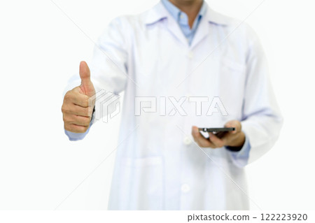 Doctor or scientist in a white lab coat standing with finger thumbs up while holding smartphone with his hand. Portrait on white background, studio shot. Doctor or scientist in a white lab coat standing with finger thumbs up while holding smartphone with his hand. Portrait on white background, studio shot. 122223920