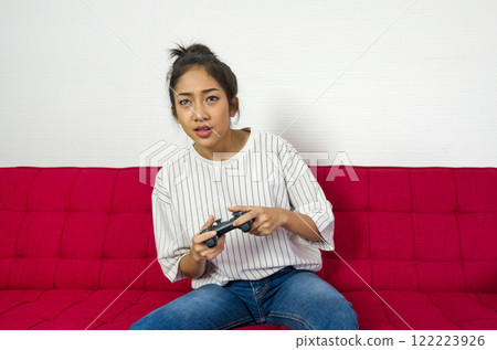Young asian woman playing console game relax in living room, enjoy leisure weekend at home. Stress free concept. Young asian woman playing console game relax in living room, enjoy leisure weekend at home. Stress free concept. 122223926