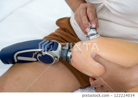 Determined woman expertly navigating a high-tech device on her leg, suggesting healthcare tech use. Determined woman expertly navigating a high-tech device on her leg, suggesting healthcare tech use. 122224034