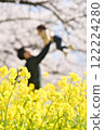 家長抱著孩子在櫻花和油菜花叢中 122224280