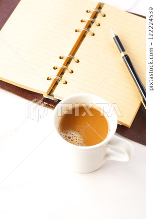 Image of a man working at his desk with a system organizer while drinking a cafe latte, a coffee with plenty of milk Image of a man working at his desk with a system organizer while drinking a cafe latte, a coffee with plenty of milk 122224539