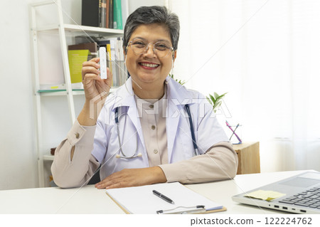 Senior female doctor holding ATK kit in hospital room, covid19 and pandemic concept. Senior female doctor holding ATK kit in hospital room, covid19 and pandemic concept. 122224762