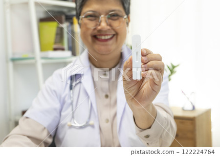 Senior female doctor holding ATK kit in hospital room, covid19 and pandemic concept. 122224764