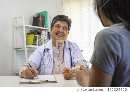 General practitioner taking notes when talking to female patient in hospital. General practitioner taking notes when talking to female patient in hospital. 122224820