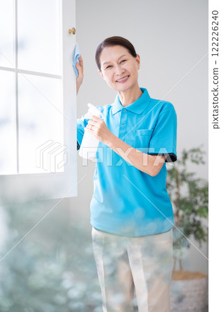 Senior female housekeeper cleaning windows Senior female housekeeper cleaning windows 122226240