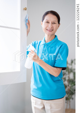 Senior female housekeeper cleaning windows Senior female housekeeper cleaning windows 122226241