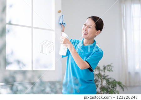 Senior female housekeeper cleaning windows Senior female housekeeper cleaning windows 122226245