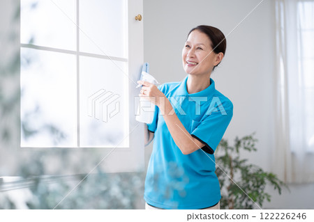 Senior female housekeeper cleaning windows 122226246