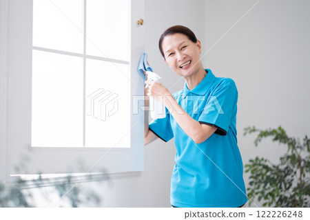 Senior female housekeeper cleaning windows 122226248