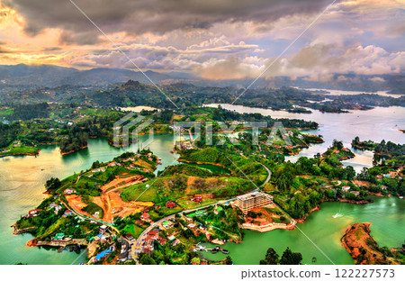 Aerial view of Guatape, Colombia at sunset, showcasing its vibrant landscapes lush green hills and a network of shimmering turquoise lakes Aerial view of Guatape, Colombia at sunset, showcasing its vibrant landscapes lush green hills and a network of shimmering turquoise lakes 122227573