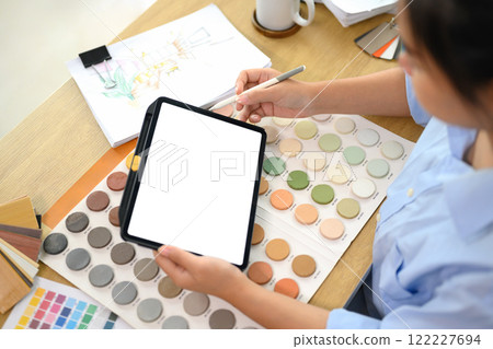 Creative woman holding digital tablet examining color swatches to new interior design project Creative woman holding digital tablet examining color swatches to new interior design project 122227694