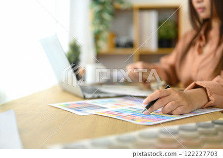 Close up of interior designer reviewing color swatches and design layouts on her desk 122227703