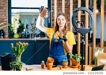 Home garden. Pretty female holding water can and cactus in pot, gardening at home. Home planting on the kitchen. Free time for little house gardening concept. 122228191