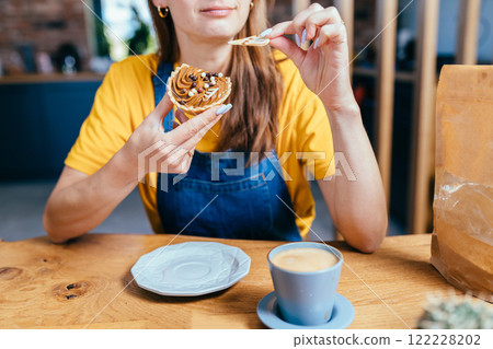 Searching for best advice. Romantic brunette haired smiling female gardener eats sweet cake, drinking coffee sitting surround her plants pots, equipment, tools watering can in home garden at home. 122228202