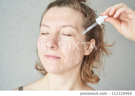 Asian female adult applying face serum with a dropper for skincare routine, eyes Asian female adult applying face serum with a dropper for skincare routine, eyes 122228469